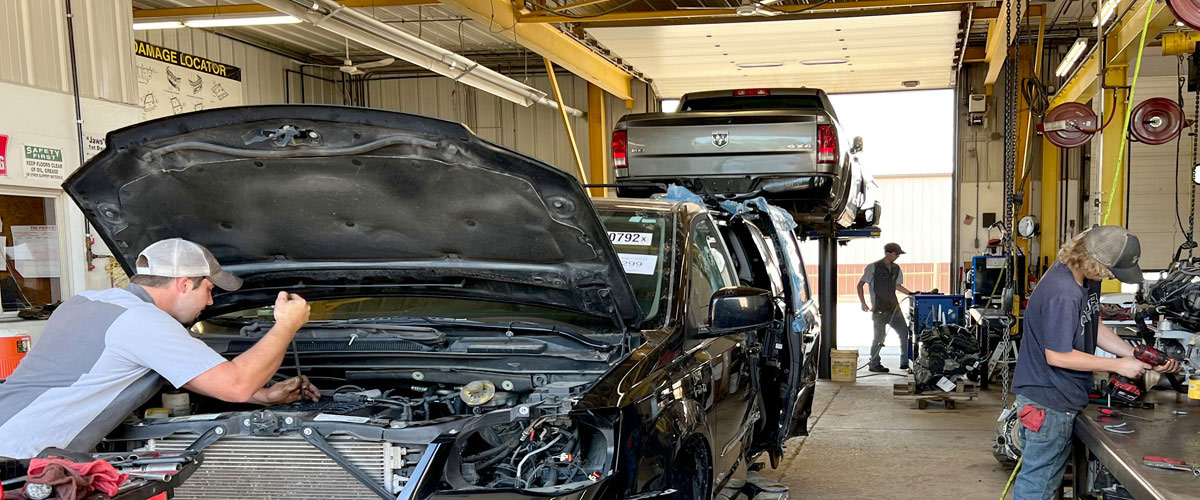 Y Yard tech disassembling parts from the engine compartment of a vehicle